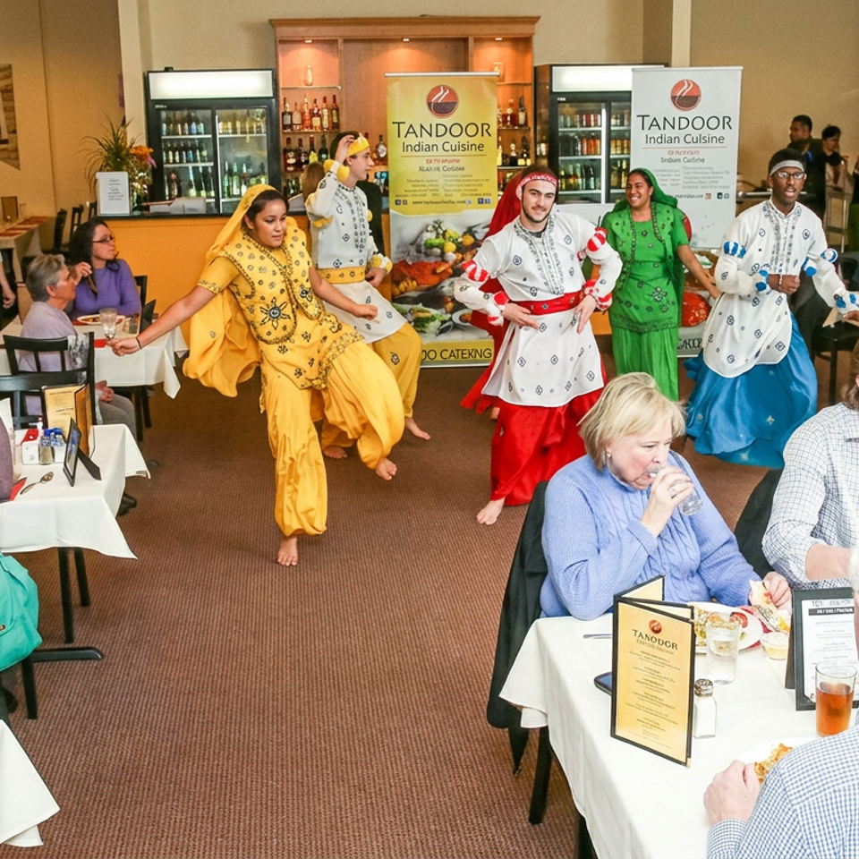 Dancers in colorful Indian costumes perform among diners inside Tandoor Indian Cuisine restaurant.