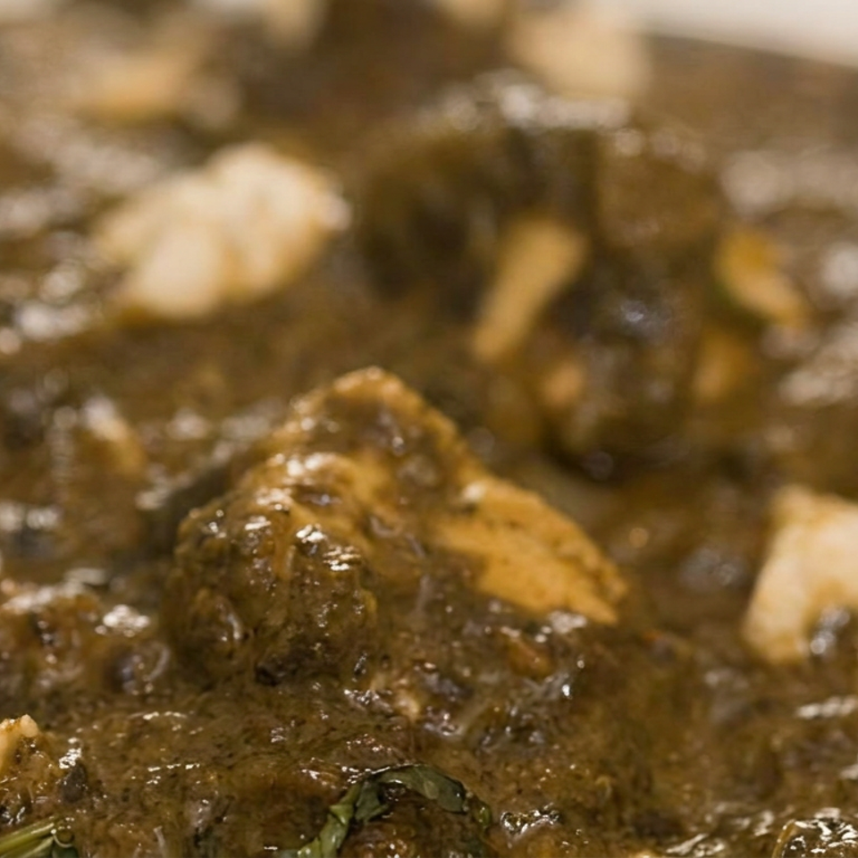 Close-up of a rich brown stew with tender chunks, herbs, and glossy sauce.